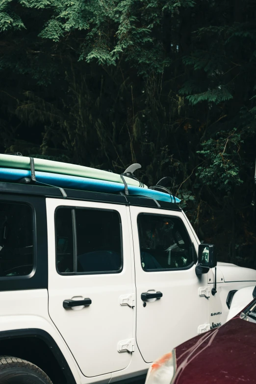 a white jeep with a blue surf board on top of it