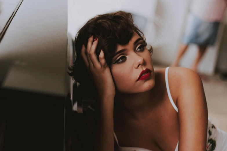 a beautiful young woman leaning against a wall