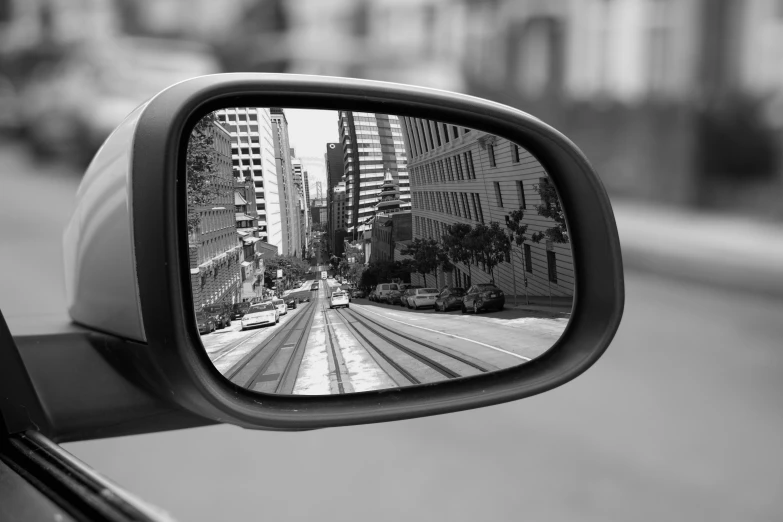 a side mirror of a car with a city view