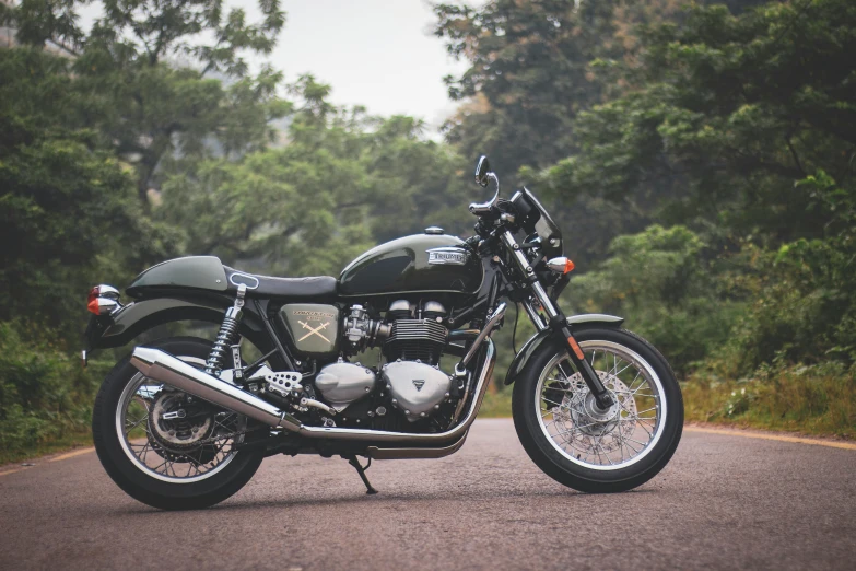 black motorcycle parked on asphalt next to trees