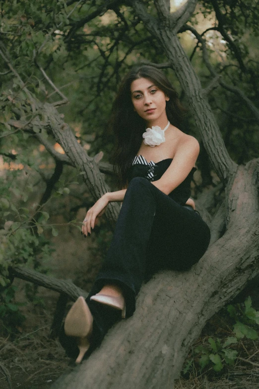 a girl sitting on a tree nch in a forest