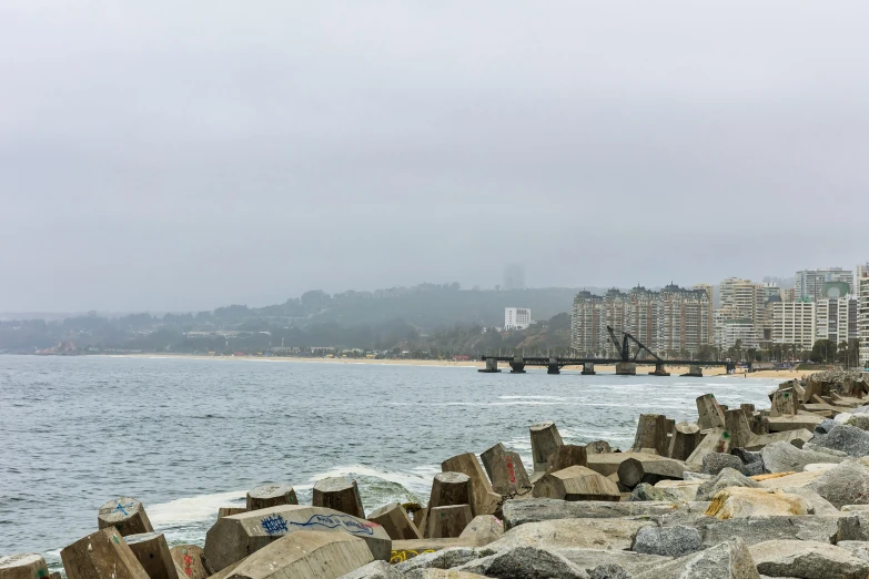 a bench overlooking the ocean and buildings on a foggy day