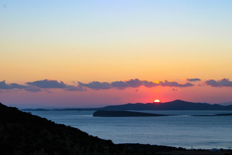 the sun rises over an island and lake