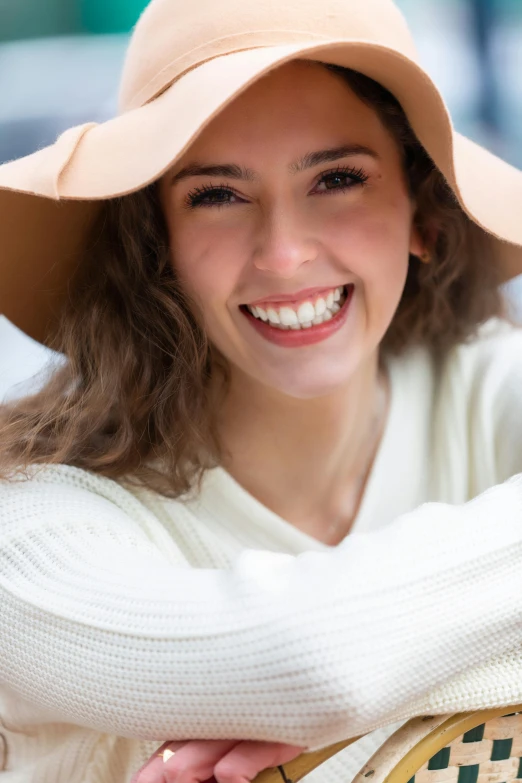 a woman in white shirt and large hat with her hand on her shoulder