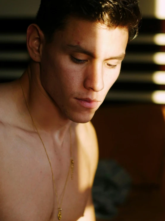 man staring at his cell phone wearing a golden necklace