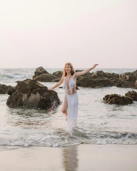 a woman is standing in the ocean wearing a white dress