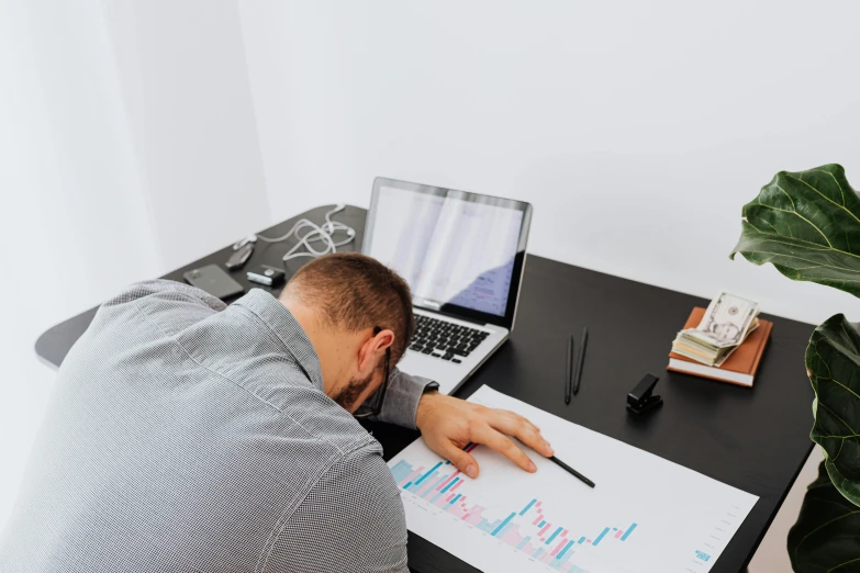 a person leaning over a desk using a laptop