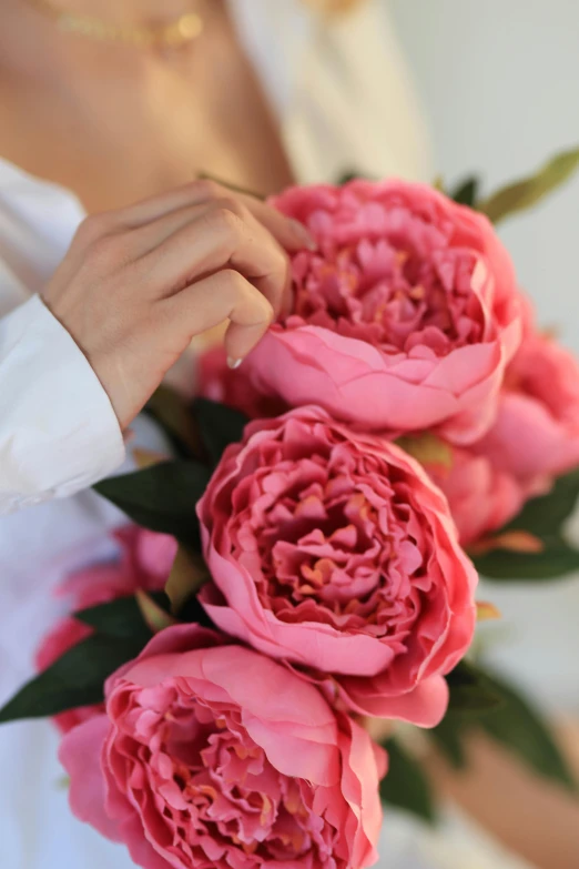 a close up of a person with their hand on a bouquet of flowers