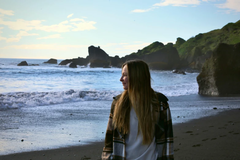 young woman with long hair looking towards the ocean