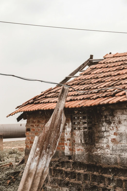 the roof of an old brick building is broken and rusted