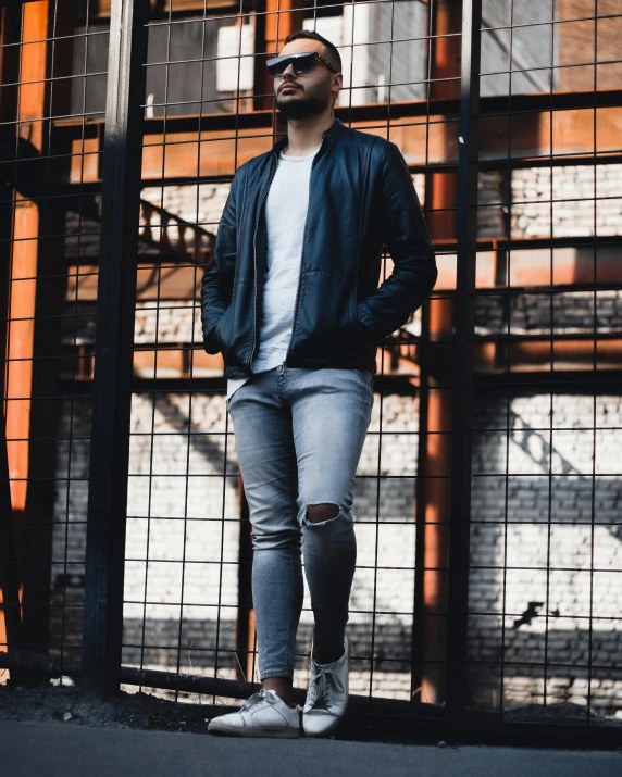 the man is standing outside near a fence