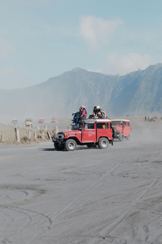 two red truck on open road with mountains in the background