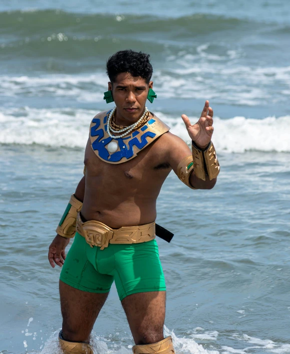 a man dressed like an egyptian warrior stands in shallow water with a surfboard