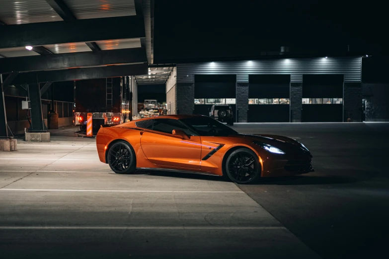 an orange sports car parked in a parking lot at night