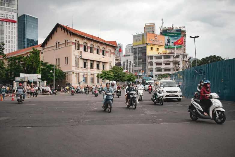 people riding scooters in an area with tall buildings