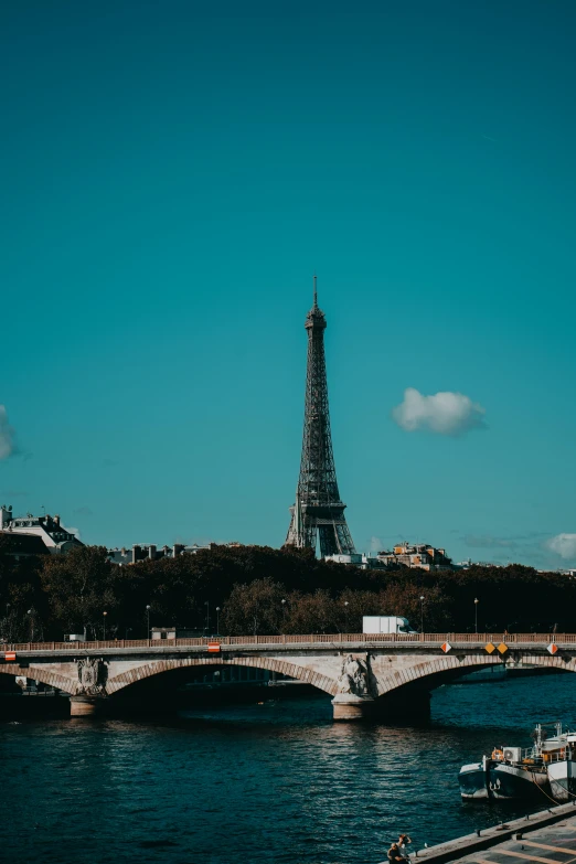 a river near a bridge and a tower with a spire