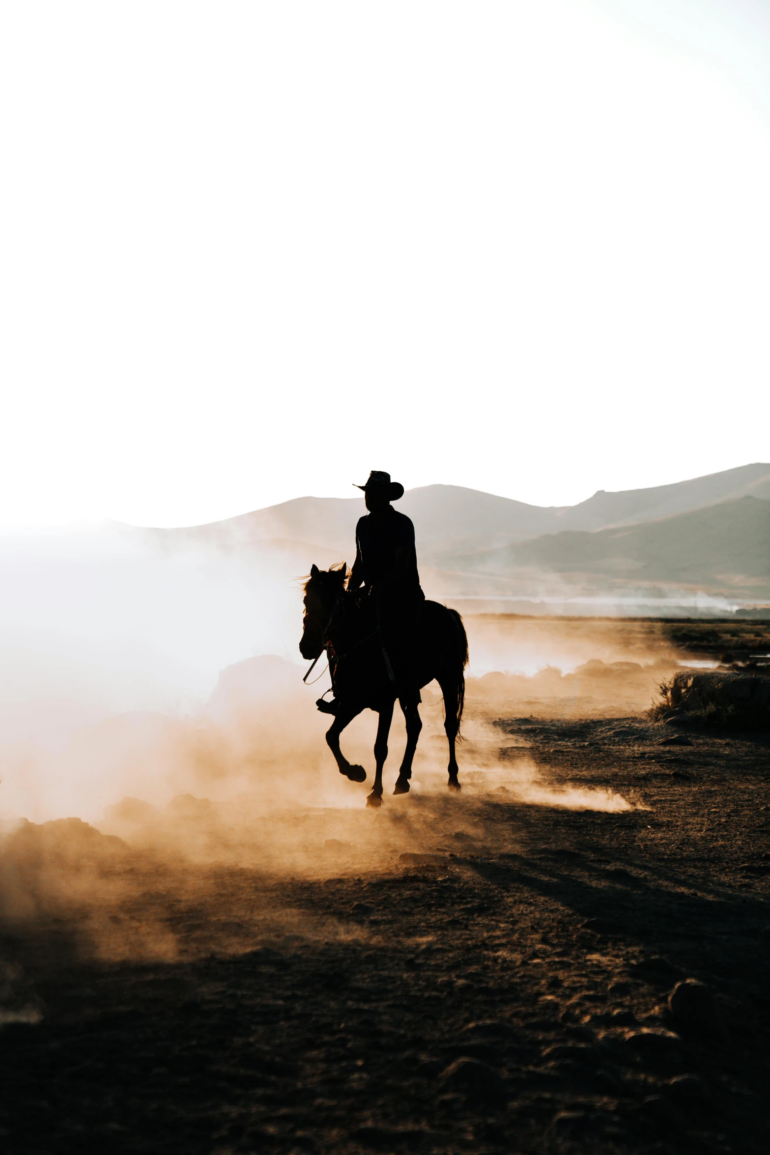 a man rides his horse with dust behind him