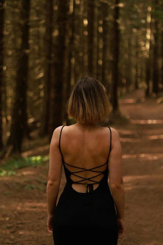 back view of a woman with brown hair walking in the forest