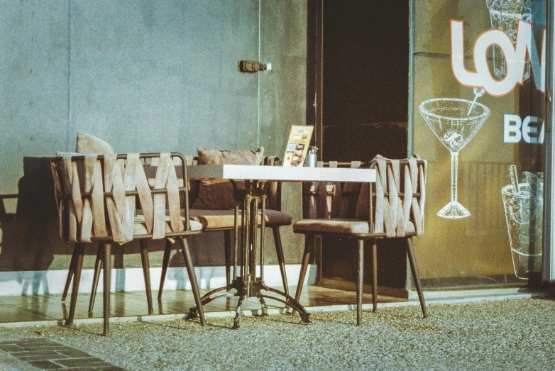 a couple of wooden chairs and table next to a window