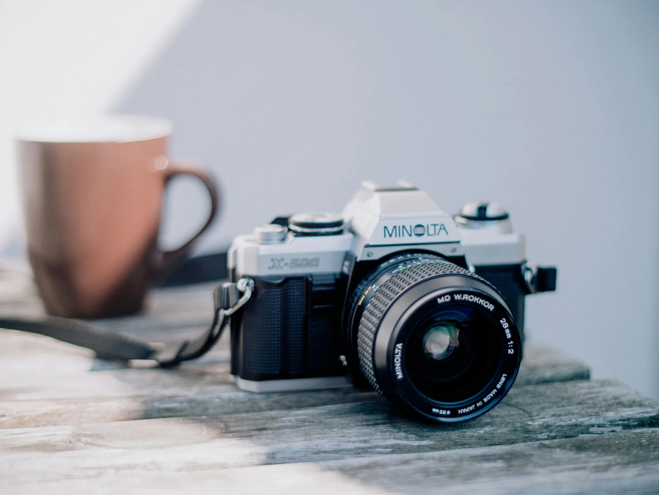 a camera with a cup of coffee and a brown mug