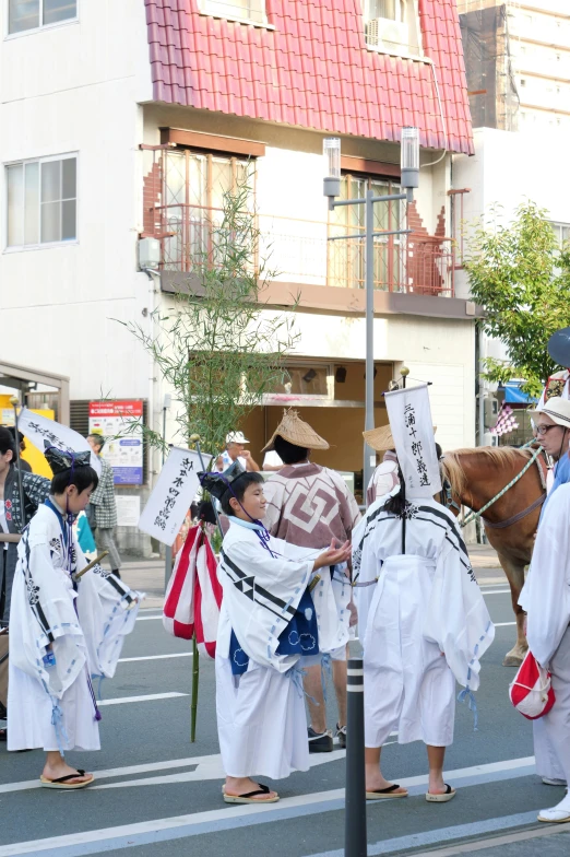 men dressed in white outfits on a street next to a horse