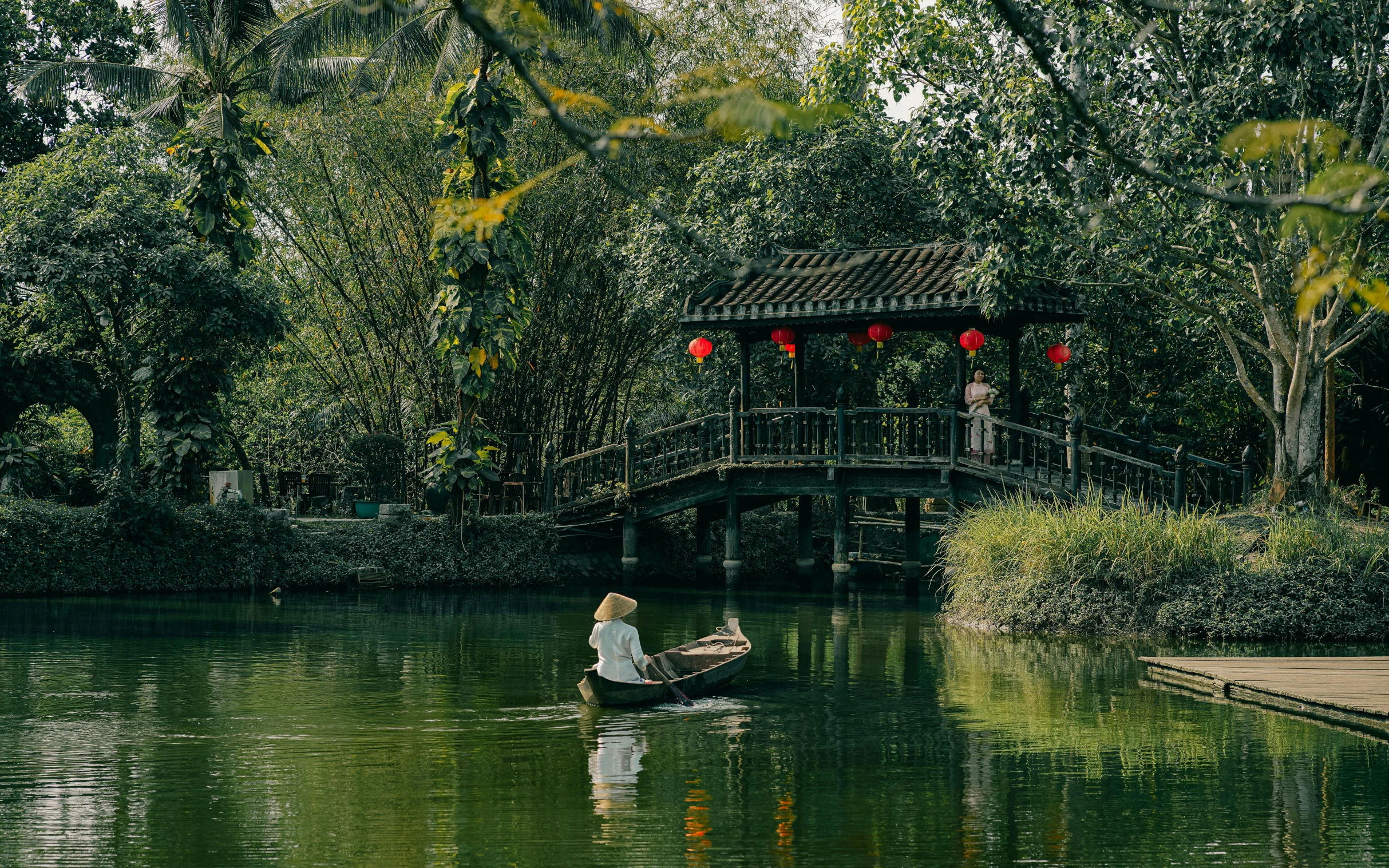 man rowing a boat with asian decorations on it in the river