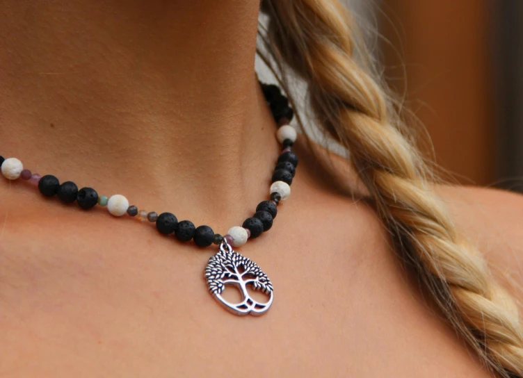 a woman is wearing a tree of life necklace with two strands