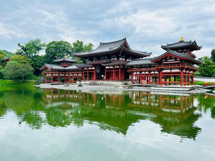 asian pavilion on calm pond with green plants in the background