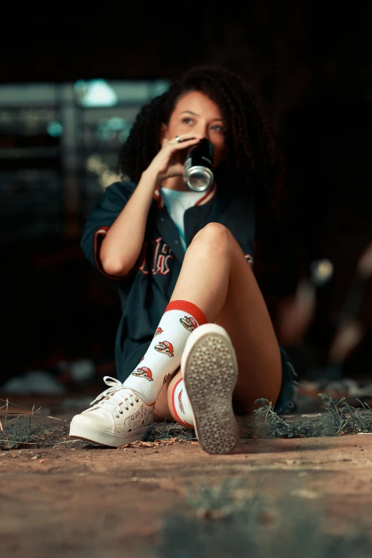 a person sitting on the ground drinking from a cup