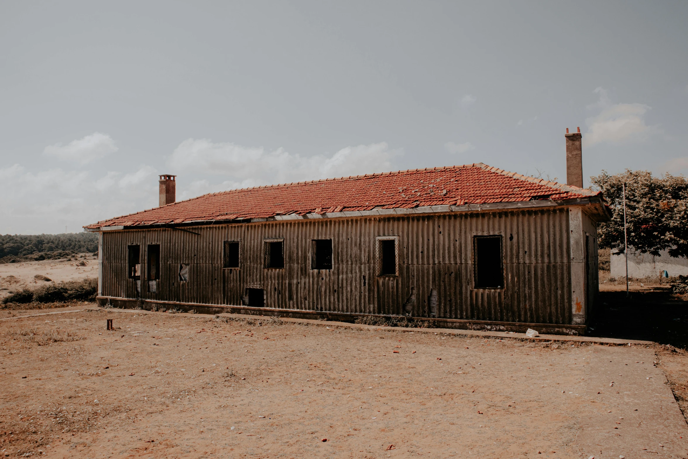 an abandoned building with a red roof and brick chimneys