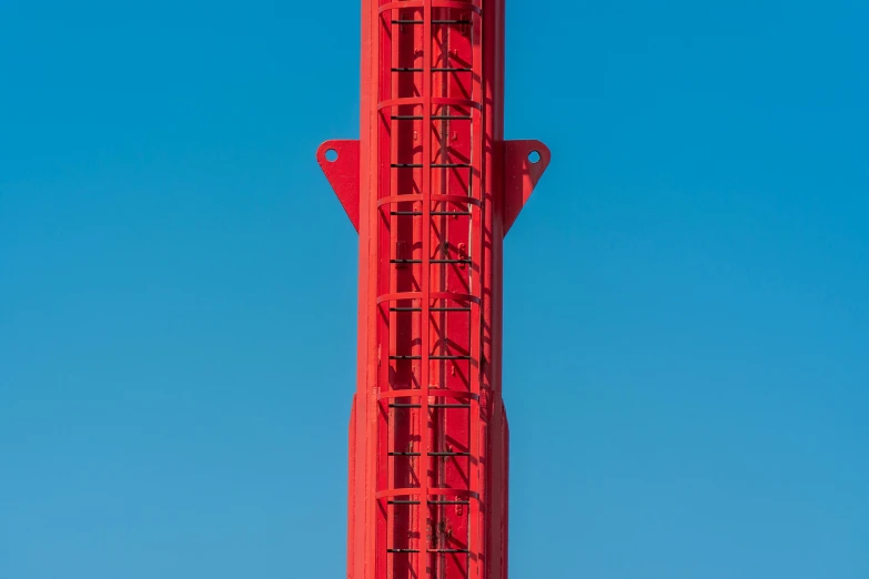 a large red clock tower against a clear blue sky