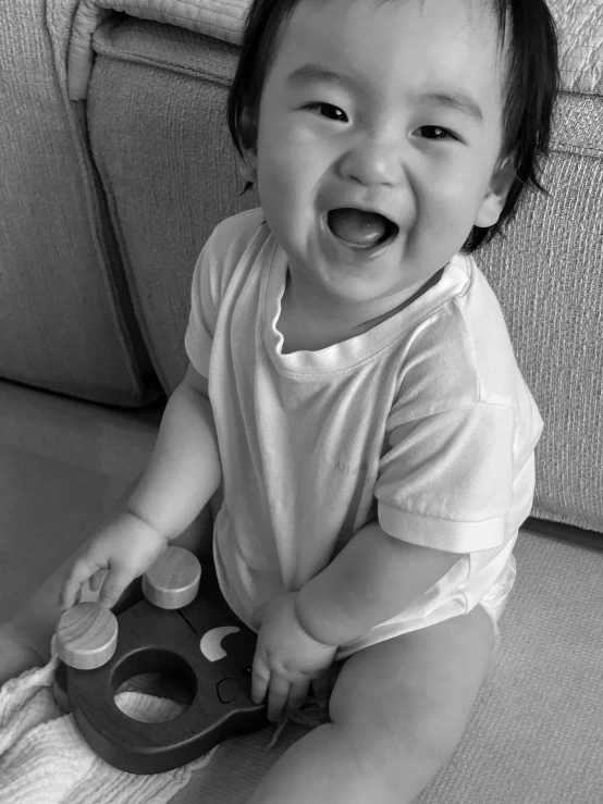 a black and white image of a smiling toddler on a couch