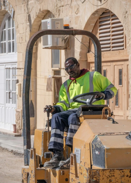 a worker in an orange safety jacket driving a machine