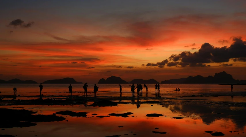 a beautiful sunset with some people playing in the water