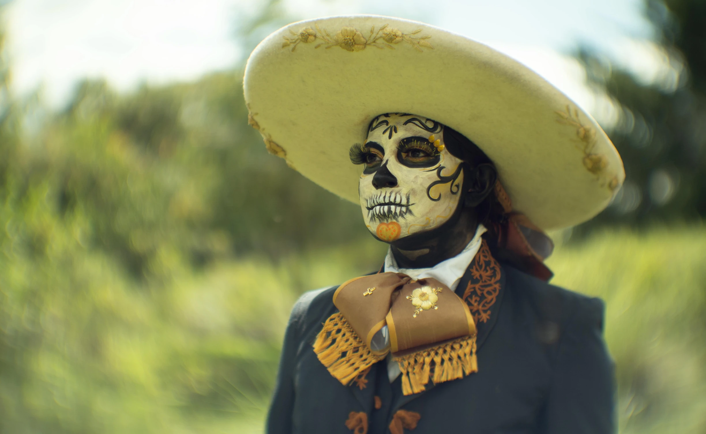 a man in a skeleton headdress, and sombrero with a flower