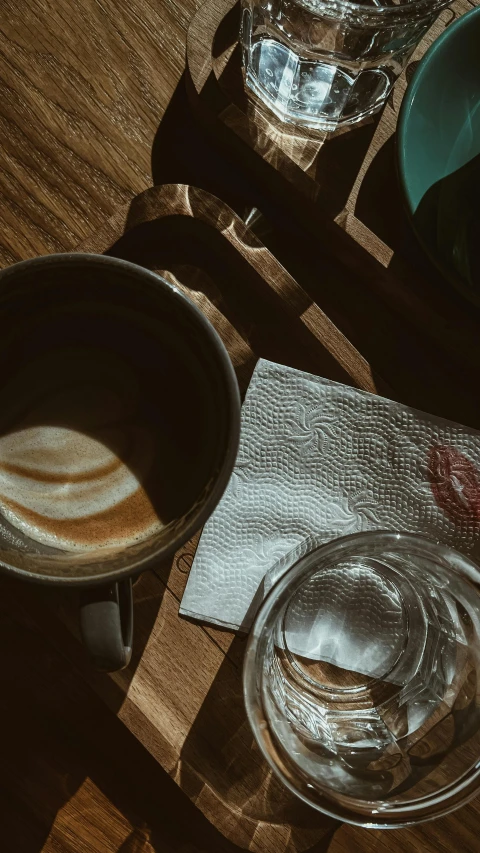 an empty plate and a glass and a bowl on a wooden table