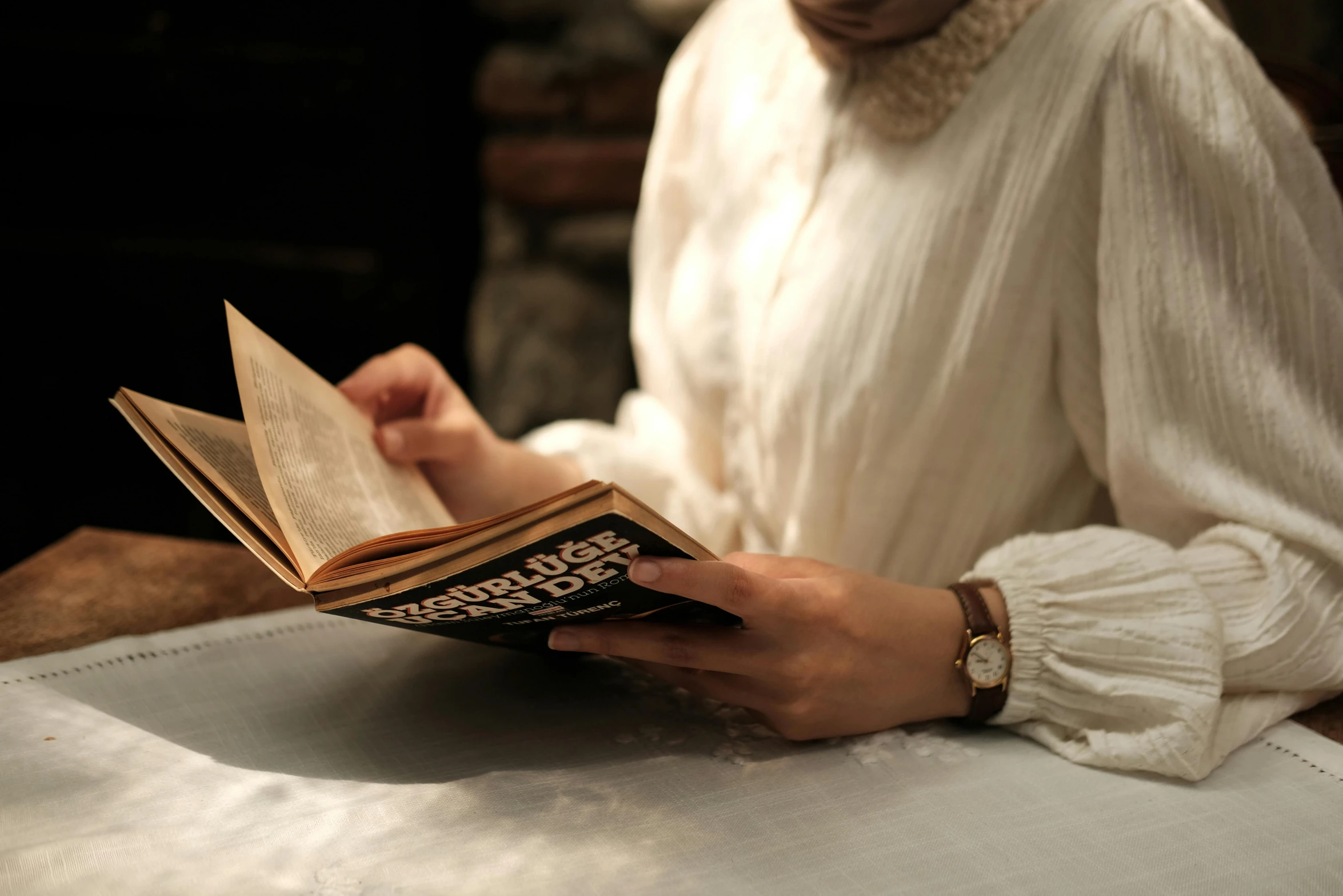 a woman reading a book on top of a white table