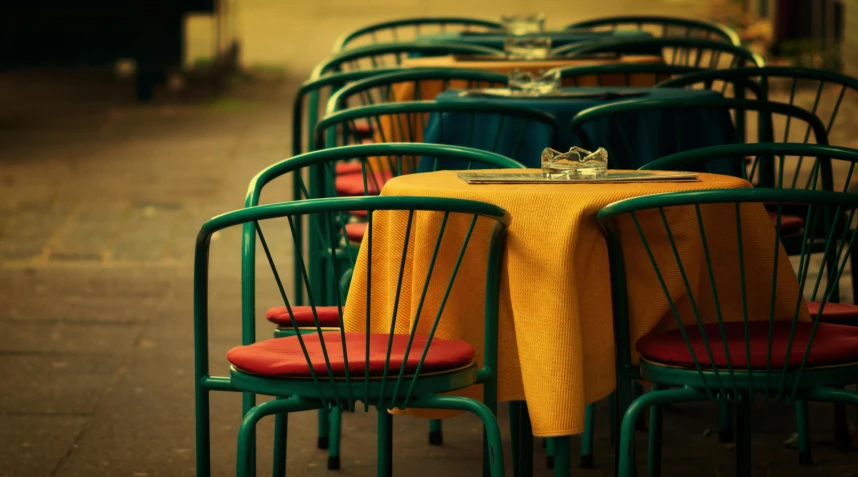 a row of green chairs with yellow linen covered table top