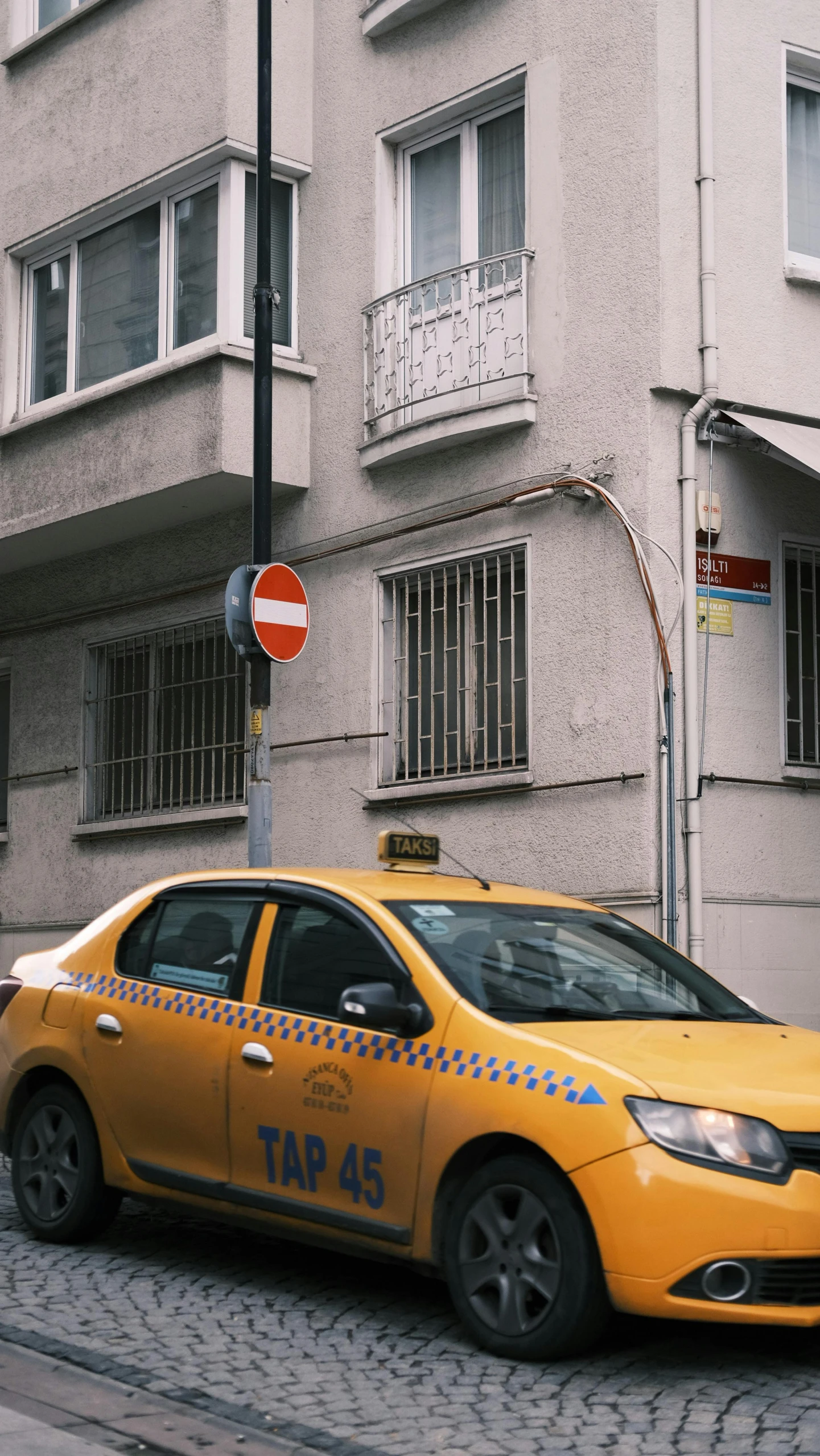 yellow taxi cab driving down street next to tall buildings