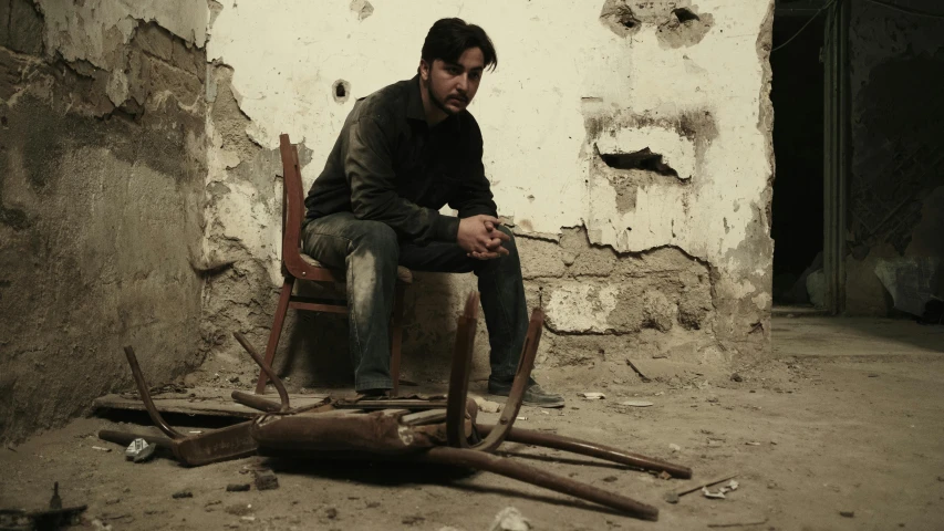 a man sits on a chair next to broken nail and wooden nches