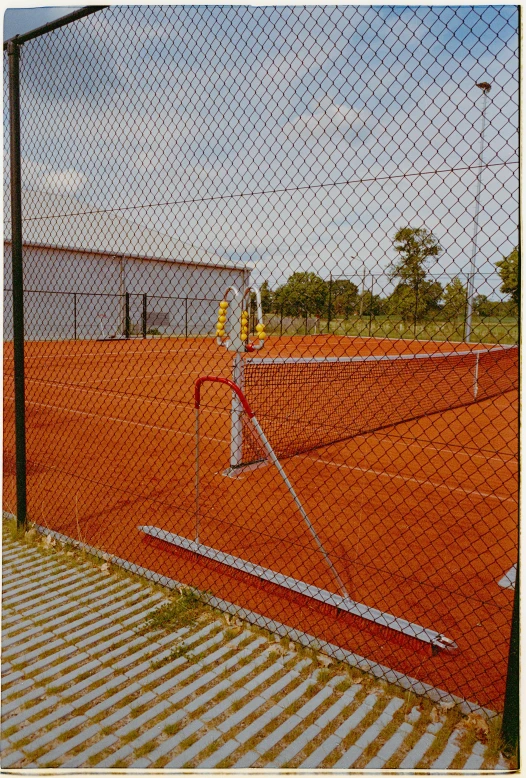 a tennis court with a net and buildings in the background