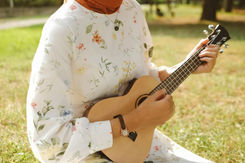 a woman sitting in the grass with her guitar