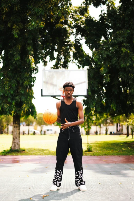 a person playing basketball on the street with trees