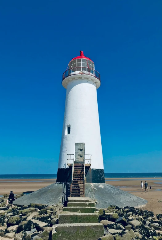 there is a white lighthouse on the beach