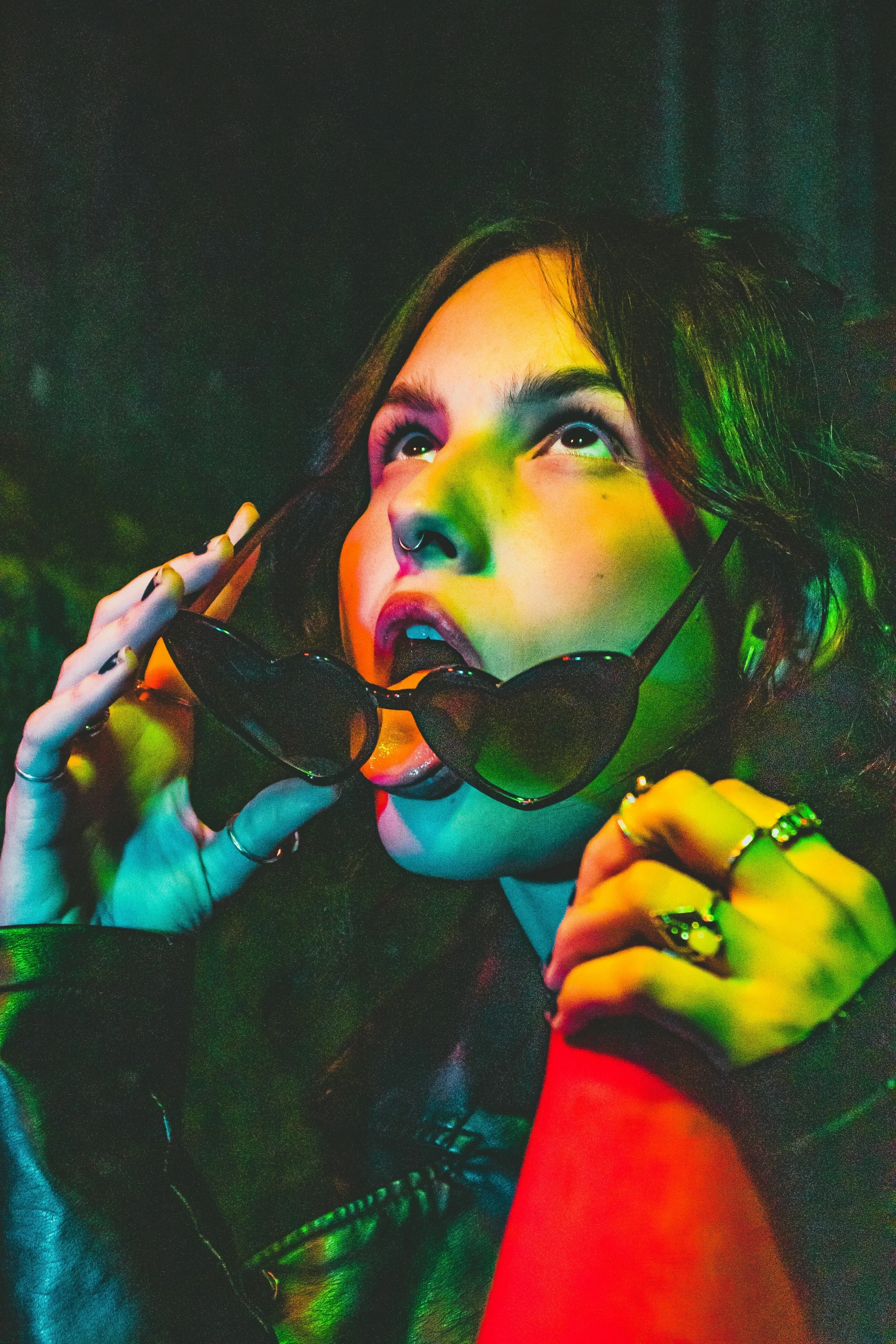 a young woman talking on her cell phone with a green and pink light shining in the background