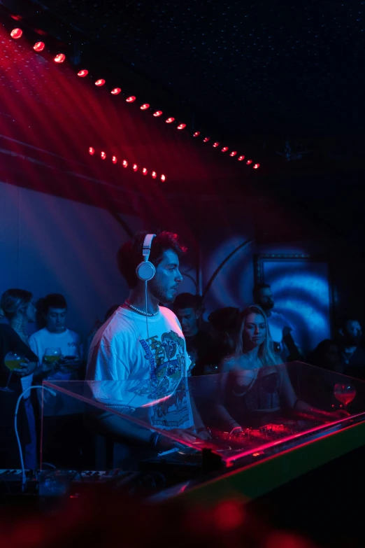 a young man at a dj mixer on stage with other people in the background