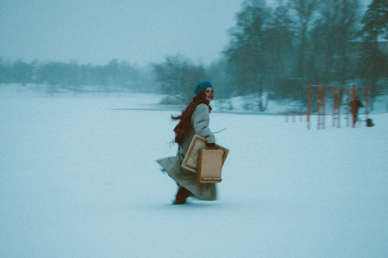 a woman walking in the snow with two bags