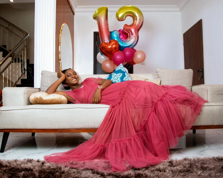 a woman lays on a couch with balloons in the air
