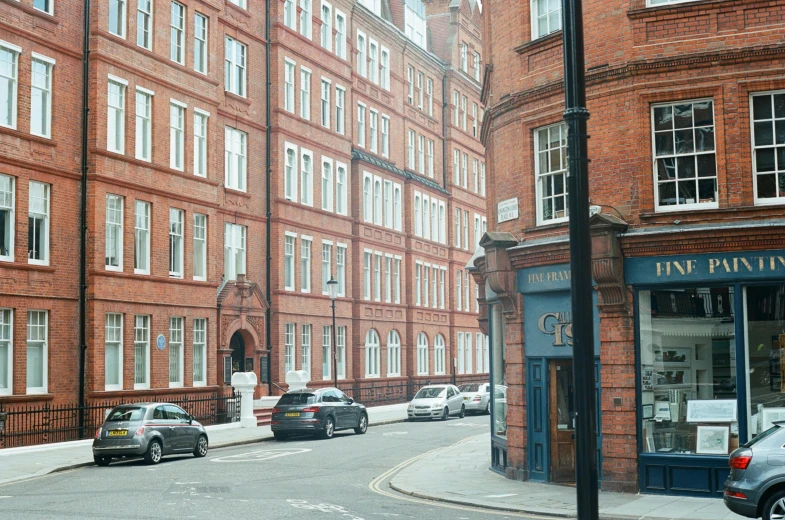 many cars are parked along the road outside a red building