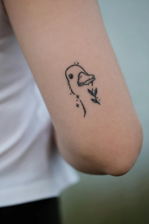 a tattoo on the arm shows a bird holding an umbrella